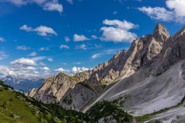 Dolomiti Alpleri güzel dağ manzarası. Dolomitlerde Rocky kulesi zirveleri. Yeşil dağ vadisindeki yürüyüş yolunda yaz manzarası ve bulutlu mavi gökyüzü.