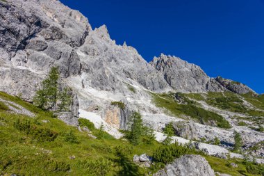 Dolomiti Alpleri güzel dağ manzarası. Dolomitlerde Rocky kulesi zirveleri. Yeşil dağ vadisindeki yürüyüş yolunda yaz manzarası ve bulutlu mavi gökyüzü.