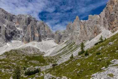 Dolomiti Alpleri güzel dağ manzarası. Dolomitlerde Rocky kulesi zirveleri. Yeşil dağ vadisindeki yürüyüş yolunda yaz manzarası ve bulutlu mavi gökyüzü.