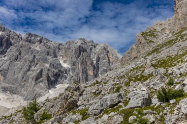 Dolomiti Alpleri güzel dağ manzarası. Dolomitlerde Rocky kulesi zirveleri. Yeşil dağ vadisindeki yürüyüş yolunda yaz manzarası ve bulutlu mavi gökyüzü.