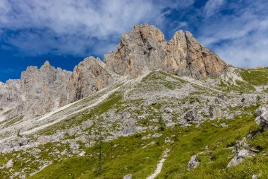 Dolomiti Alpleri güzel dağ manzarası. Dolomitlerde Rocky kulesi zirveleri. Yeşil dağ vadisindeki yürüyüş yolunda yaz manzarası ve bulutlu mavi gökyüzü.