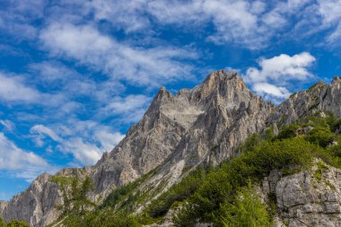 Dolomiti Alpleri güzel dağ manzarası. Dolomitlerde Rocky kulesi zirveleri. Yeşil dağ vadisindeki yürüyüş yolunda yaz manzarası ve bulutlu mavi gökyüzü.