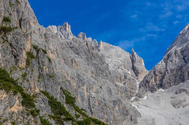 Dolomiti Alpleri güzel dağ manzarası. Dolomitlerde Rocky kulesi zirveleri. Yeşil dağ vadisindeki yürüyüş yolunda yaz manzarası ve bulutlu mavi gökyüzü.