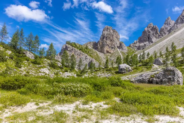 Dolomiti Alpleri güzel dağ manzarası. Dolomitlerde Rocky kulesi zirveleri. Yeşil dağ vadisindeki yürüyüş yolunda yaz manzarası ve bulutlu mavi gökyüzü.