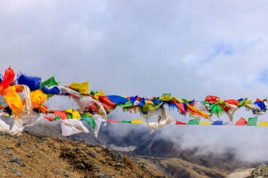 Nepal 'in görkemli dağlarında dalgalanan renkli Nepal ve Tibet dua bayrakları. Barışı, merhameti ve bereketi simgeleyen bayraklar Himalaya dağlarının sakin manzarasını süslüyor.