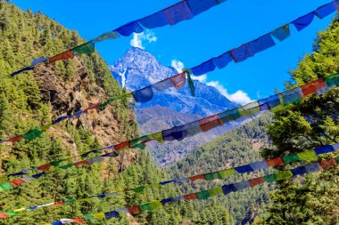 Nepal 'in görkemli dağlarında dalgalanan renkli Nepal ve Tibet dua bayrakları. Barışı, merhameti ve bereketi simgeleyen bayraklar Himalaya dağlarının sakin manzarasını süslüyor.