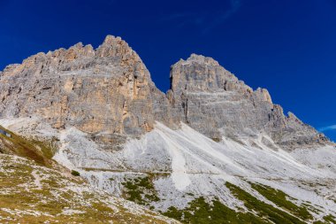 Dolomitler yaz aylarında mavi gökyüzünün altında güzel bir kaya kulesi oluştururlar. İtalyan Alp Dağları yüksek rakımlı kayalık duvarların manzaralı manzarası uçurumun görkemli manzarası ve yeşil vadi
