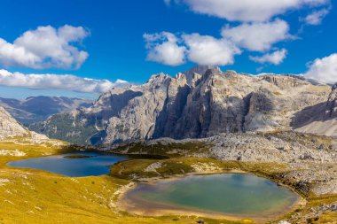 Dolomitler yaz aylarında mavi gökyüzünün altında güzel bir kaya kulesi oluştururlar. İtalyan Alp Dağları yüksek rakımlı kayalık duvarların manzaralı manzarası uçurumun görkemli manzarası ve yeşil vadi