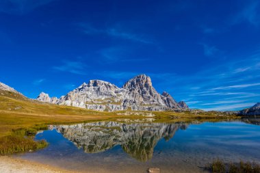 Dolomitler yaz aylarında mavi gökyüzünün altında güzel bir kaya kulesi oluştururlar. İtalyan Alp Dağları yüksek rakımlı kayalık duvarların manzaralı manzarası uçurumun görkemli manzarası ve yeşil vadi