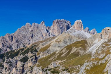 Dolomitler yaz aylarında mavi gökyüzünün altında güzel bir kaya kulesi oluştururlar. İtalyan Alp Dağları yüksek rakımlı kayalık duvarların manzaralı manzarası uçurumun görkemli manzarası ve yeşil vadi
