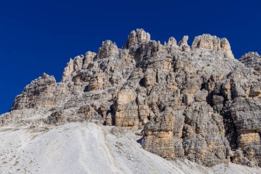 Dolomitler yaz aylarında mavi gökyüzünün altında güzel bir kaya kulesi oluştururlar. İtalyan Alp Dağları yüksek rakımlı kayalık duvarların manzaralı manzarası uçurumun görkemli manzarası ve yeşil vadi