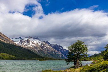 El Chalten, Arjantin 'deki Patagonya dağları. Monte Fitzroy ve Cerro Torre göl kıyısındaki granit duvarlara tırmanıyor. Buz dağları yüzen buzdağları ve kara bulutlarla. Patagonya havası ve dağ sıraları.