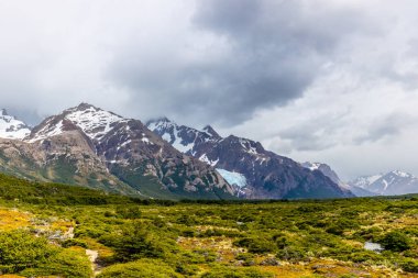 El Chalten, Arjantin 'deki Patagonya dağları. Monte Fitzroy ve Cerro Torre göl kıyısındaki granit duvarlara tırmanıyor. Buz dağları yüzen buzdağları ve kara bulutlarla. Patagonya havası ve dağ sıraları.