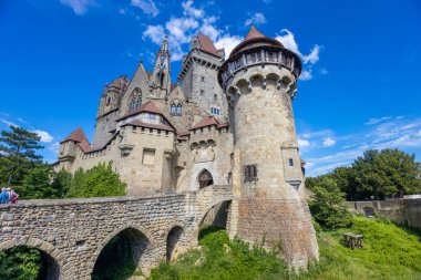 Mavi gökyüzünün altındaki kale simgesi. Avusturya 'da ortaçağ kalesi. Viyana çevresindeki antik tarihi yerler. Burg Kreuzenstein Kalesi. Dışarıdan kuleleri olan eski antik bir kale.