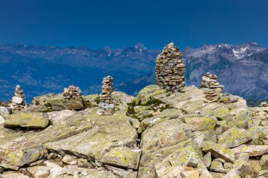 Stone pyramid in the mountains on the summit and ountain pass marking the trail clipart