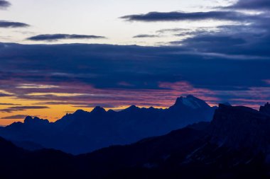 Dolomitlerde gün batımı dağ siluetleri ve arka planda yanan kırmızı gökyüzü olan güzel bir manzara. Doloiti Alplerinde gün doğumu ve gün batımı