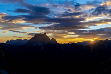 Dolomitlerde gün batımı dağ siluetleri ve arka planda yanan kırmızı gökyüzü olan güzel bir manzara. Doloiti Alplerinde gün doğumu ve gün batımı