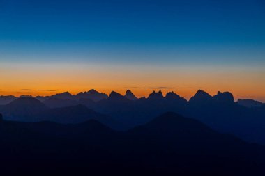 Dolomitlerde gün batımı dağ siluetleri ve arka planda yanan kırmızı gökyüzü olan güzel bir manzara. Doloiti Alplerinde gün doğumu ve gün batımı