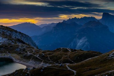 Dolomitlerde gün batımı dağ siluetleri ve arka planda yanan kırmızı gökyüzü olan güzel bir manzara. Doloiti Alplerinde gün doğumu ve gün batımı