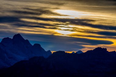 Dolomitlerde gün batımı dağ siluetleri ve arka planda yanan kırmızı gökyüzü olan güzel bir manzara. Doloiti Alplerinde gün doğumu ve gün batımı