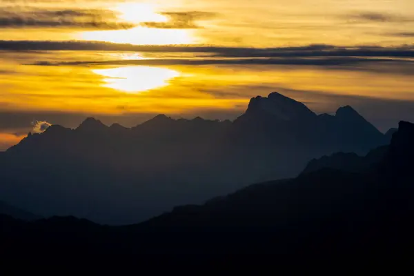Dolomitlerde gün batımı dağ siluetleri ve arka planda yanan kırmızı gökyüzü olan güzel bir manzara. Doloiti Alplerinde gün doğumu ve gün batımı