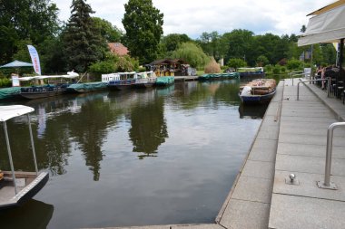 Bu büyüleyici görüntü, Almanya 'nın pitoresk bir bölgesi olan Lubbenau / Spreewald' ın dingin güzelliğini yansıtıyor. Fotoğrafta yemyeşil sularda salınan sakin bir kanal var. Geleneksel tekneler suyun üzerinde nazikçe yüzüyor. Yoğun orman