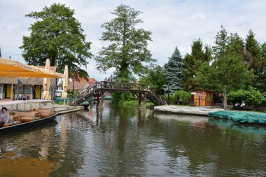 Bu büyüleyici görüntü, Almanya 'nın pitoresk bir bölgesi olan Lubbenau / Spreewald' ın dingin güzelliğini yansıtıyor. Fotoğrafta yemyeşil sularda salınan sakin bir kanal var. Geleneksel tekneler suyun üzerinde nazikçe yüzüyor. Yoğun orman