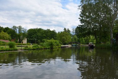 Bu büyüleyici görüntü, Almanya 'nın pitoresk bir bölgesi olan Lubbenau / Spreewald' ın dingin güzelliğini yansıtıyor. Fotoğrafta yemyeşil sularda salınan sakin bir kanal var. Geleneksel tekneler suyun üzerinde nazikçe yüzüyor. Yoğun orman