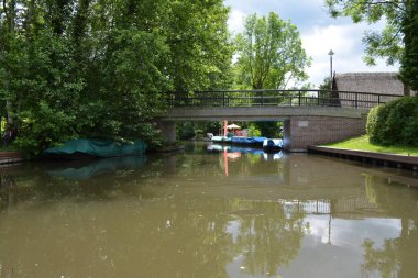 Bu büyüleyici görüntü, Almanya 'nın pitoresk bir bölgesi olan Lubbenau / Spreewald' ın dingin güzelliğini yansıtıyor. Fotoğrafta yemyeşil sularda salınan sakin bir kanal var. Geleneksel tekneler suyun üzerinde nazikçe yüzüyor. Yoğun orman
