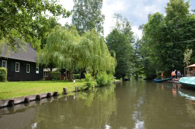 Bu büyüleyici görüntü, Almanya 'nın pitoresk bir bölgesi olan Lubbenau / Spreewald' ın dingin güzelliğini yansıtıyor. Fotoğrafta yemyeşil sularda salınan sakin bir kanal var. Geleneksel tekneler suyun üzerinde nazikçe yüzüyor. Yoğun orman