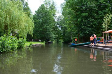 Bu büyüleyici görüntü, Almanya 'nın pitoresk bir bölgesi olan Lubbenau / Spreewald' ın dingin güzelliğini yansıtıyor. Fotoğrafta yemyeşil sularda salınan sakin bir kanal var. Geleneksel tekneler suyun üzerinde nazikçe yüzüyor. Yoğun orman