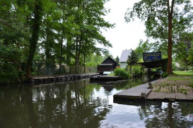 Bu büyüleyici görüntü, Almanya 'nın pitoresk bir bölgesi olan Lubbenau / Spreewald' ın dingin güzelliğini yansıtıyor. Fotoğrafta yemyeşil sularda salınan sakin bir kanal var. Geleneksel tekneler suyun üzerinde nazikçe yüzüyor. Yoğun orman