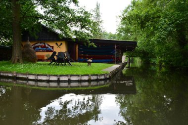 Bu büyüleyici görüntü, Almanya 'nın pitoresk bir bölgesi olan Lubbenau / Spreewald' ın dingin güzelliğini yansıtıyor. Fotoğrafta yemyeşil sularda salınan sakin bir kanal var. Geleneksel tekneler suyun üzerinde nazikçe yüzüyor. Yoğun orman