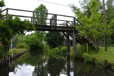 Bu büyüleyici görüntü, Almanya 'nın pitoresk bir bölgesi olan Lubbenau / Spreewald' ın dingin güzelliğini yansıtıyor. Fotoğrafta yemyeşil sularda salınan sakin bir kanal var. Geleneksel tekneler suyun üzerinde nazikçe yüzüyor. Yoğun orman