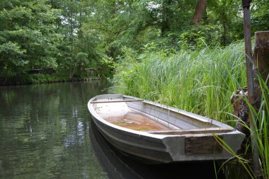 Bu büyüleyici görüntü, Almanya 'nın pitoresk bir bölgesi olan Lubbenau / Spreewald' ın dingin güzelliğini yansıtıyor. Fotoğrafta yemyeşil sularda salınan sakin bir kanal var. Geleneksel tekneler suyun üzerinde nazikçe yüzüyor. Yoğun orman