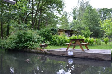 Bu büyüleyici görüntü, Almanya 'nın pitoresk bir bölgesi olan Lubbenau / Spreewald' ın dingin güzelliğini yansıtıyor. Fotoğrafta yemyeşil sularda salınan sakin bir kanal var. Geleneksel tekneler suyun üzerinde nazikçe yüzüyor. Yoğun orman