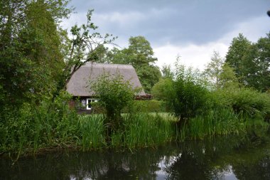 Bu büyüleyici görüntü, Almanya 'nın pitoresk bir bölgesi olan Lubbenau / Spreewald' ın dingin güzelliğini yansıtıyor. Fotoğrafta yemyeşil sularda salınan sakin bir kanal var. Geleneksel tekneler suyun üzerinde nazikçe yüzüyor. Yoğun orman