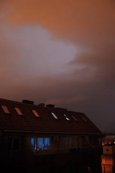 Belirgin bulutlu bir gökyüzüne karşı bir evin çatısını gösteren bir görüntü ilgi çekici bir atmosfer ve büyüleyici bir manzara yaratıyor.