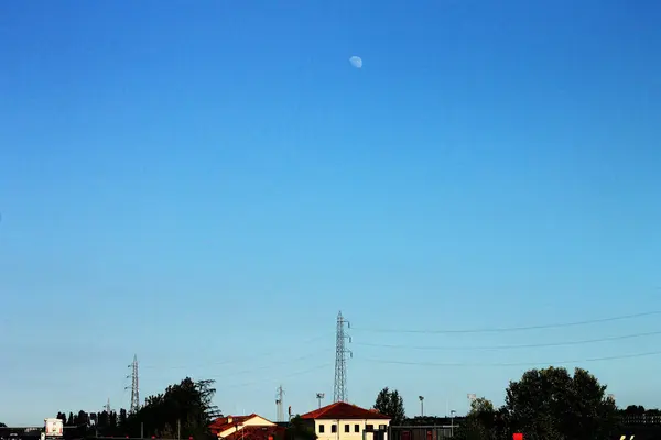 Huzurlu bir manzara engin, berrak bir mavi gökyüzünü gösteriyor. Ay huzurlu bir kırsal bölgeye dikkatlice bakıyor, İtalya.