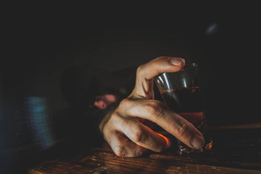 Yalnız, bunalımlı, genç bir adamın bir kadeh viskiyle kendinden geçmiş portresi.