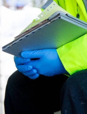 Lateks eldiven giyen bir sağlık görevlisi ilk yardım gösterisinde hasta gelir formu tutuyor..