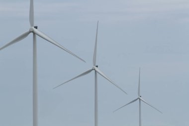 Temiz, basit bir gökyüzüne karşı üç rüzgar türbini senkronize oluyor..