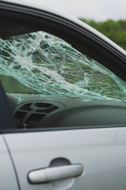 Parçalanmış ön camlı ve dağınık camlı arabanın iç manzarası. Torpido gözünün üstündeki güvenlik camında çatlaklar var..