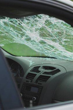 Parçalanmış ön camlı ve dağınık camlı arabanın iç manzarası. Torpido gözünün üstündeki güvenlik camında çatlaklar var..