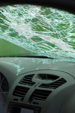 Parçalanmış ön camlı ve dağınık camlı arabanın iç manzarası. Torpido gözünün üstündeki güvenlik camında çatlaklar var..