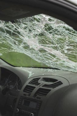 Ön camları kırılmış ve ön panelinde kırık camlar olan arabanın iç manzarası. Çarpışma hasarı güvenlik camında görülüyor..