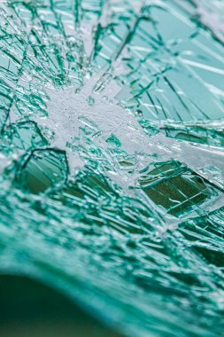 Kırık bir ön camda, ağımsı çatlaklar var. Çarpışmadan dolayı kırılan yeşil renkli güvenlik camı..