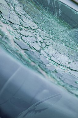 Kırık ön cam ve parlak çatlaklar. Hasarlı bir güvenlik camındaki örümcek ağı çatlaklarına yakın çekim.