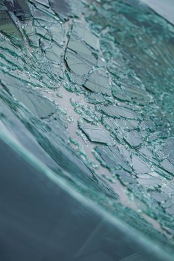 Kırık ön cam ve parlak çatlaklar. Hasarlı bir güvenlik camındaki örümcek ağı çatlaklarına yakın çekim.