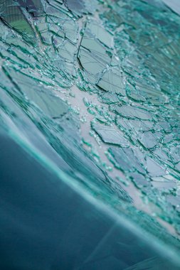 Kırık ön cam ve parlak çatlaklar. Hasarlı bir güvenlik camındaki örümcek ağı çatlaklarına yakın çekim.